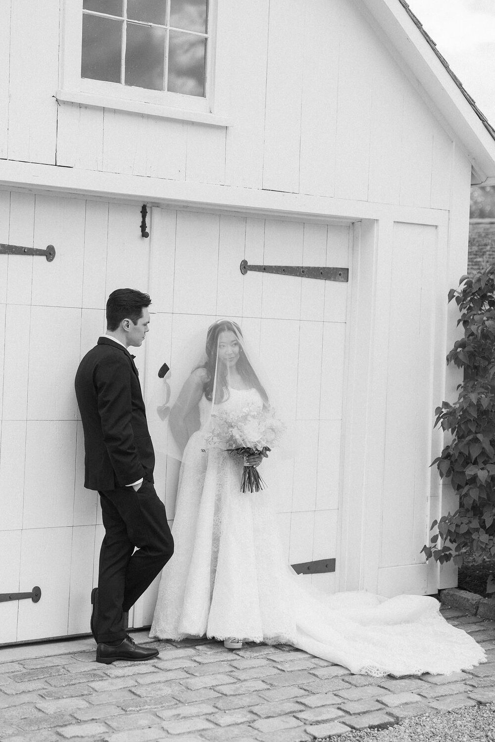 Black and white portrait of a couple beside a barn door