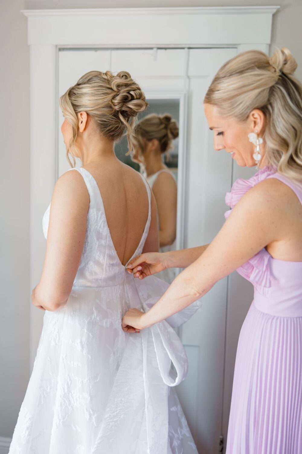 Bride's gown being fastened at the back before her wedding