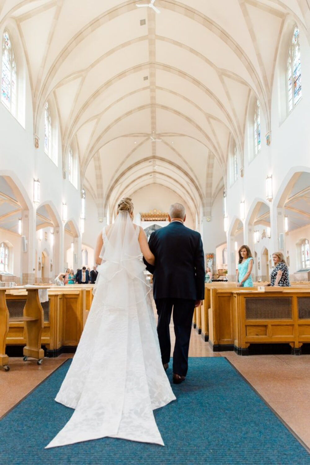 Bride walking down a cathedral aisle, gown train flowing behind