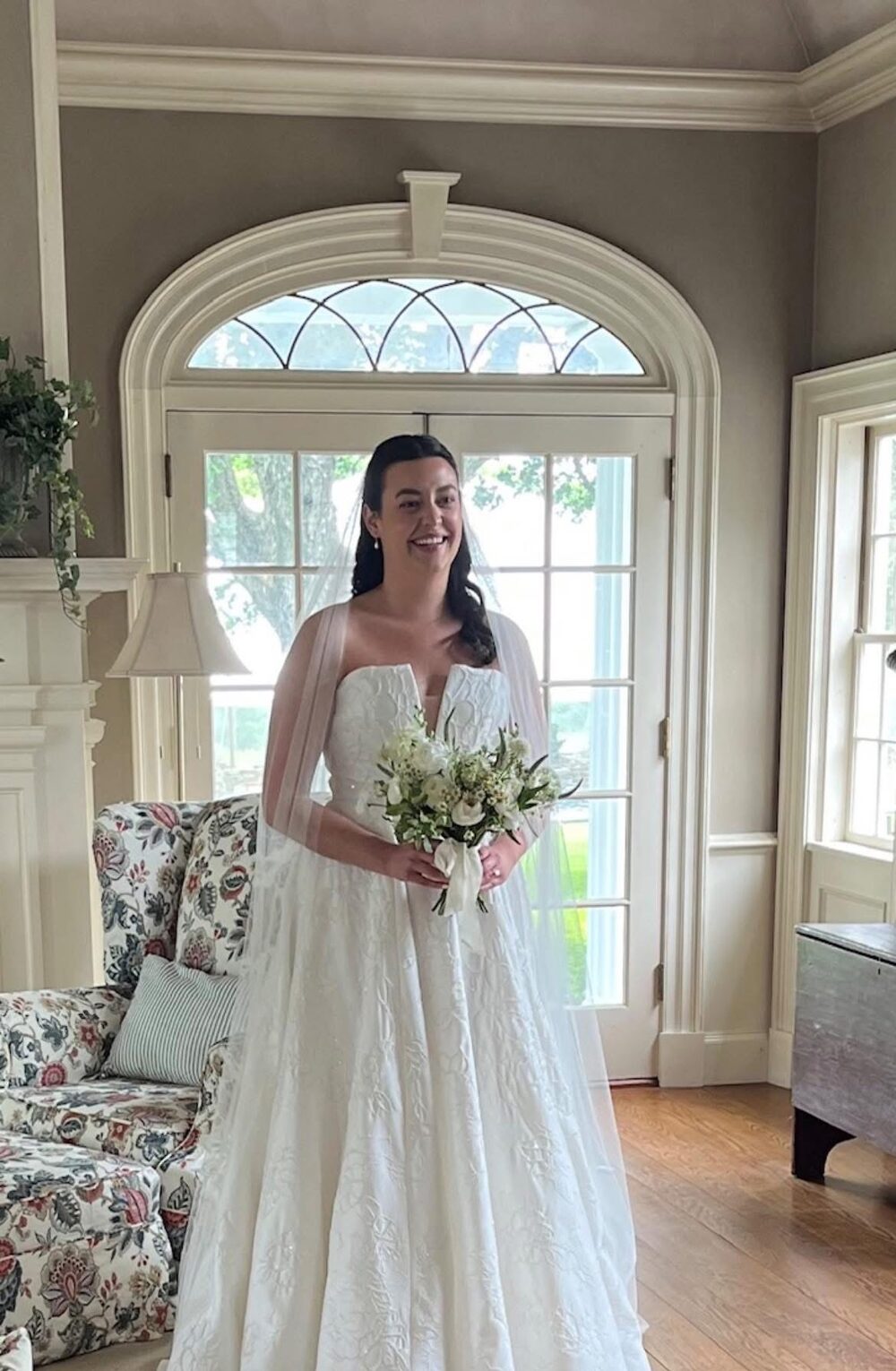 Smiling bride in a strapless gown and cape veil